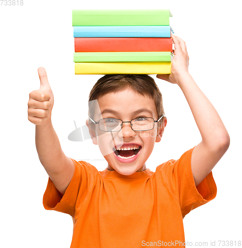 Image of Little boy is holding a pile of books