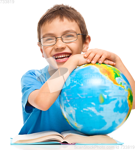 Image of Little boy is examining globe