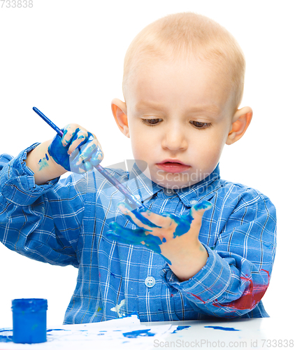 Image of Little boy is playing with paints