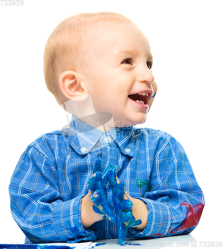 Image of Little boy is playing with paints