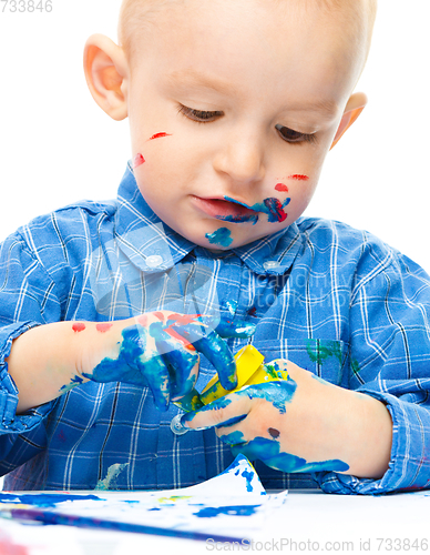 Image of Little boy is playing with paints