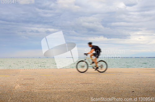 Image of Man riding a bicycle waterfront