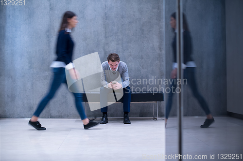 Image of businessman using mobile phone while sitting on the bench