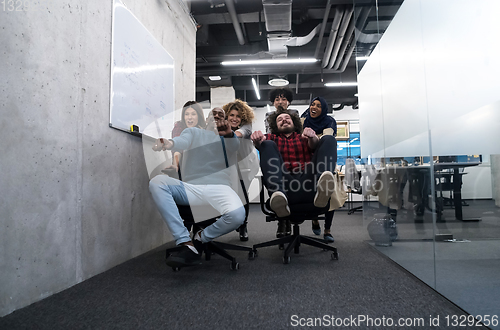 Image of multiethnics business team racing on office chairs