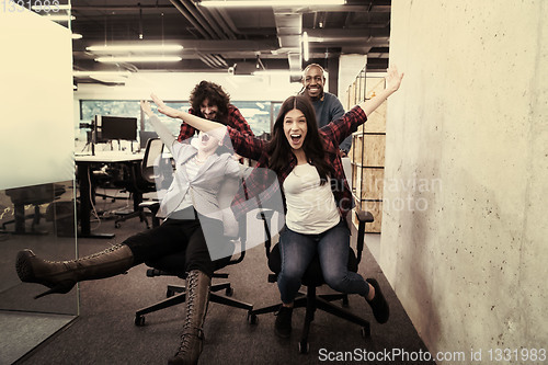 Image of multiethnics business team racing on office chairs
