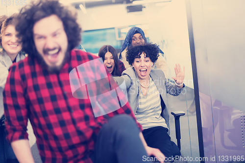 Image of multiethnics business team racing on office chairs