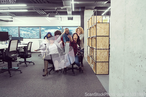 Image of multiethnics business team racing on office chairs