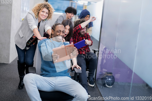 Image of multiethnics business team racing on office chairs