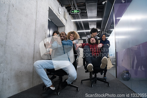 Image of multiethnics business team racing on office chairs