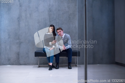 Image of business couple using mobile phone while sitting on the bench