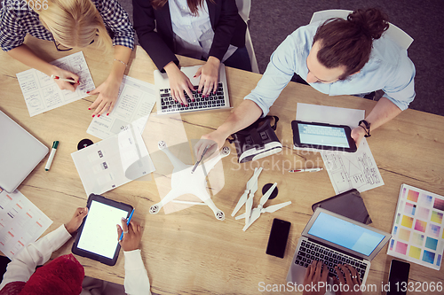 Image of top view of multiethnic business team learning about drone techn