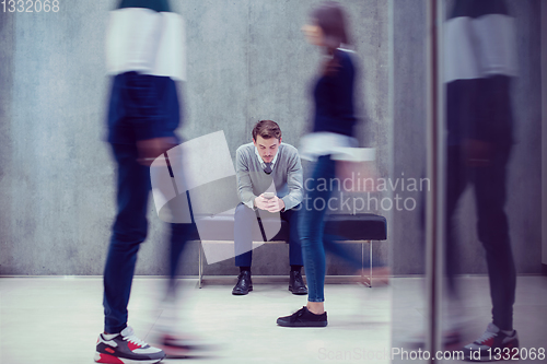 Image of businessman using mobile phone while sitting on the bench