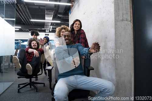 Image of multiethnics business team racing on office chairs