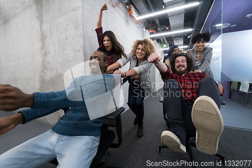 Image of multiethnics business team racing on office chairs