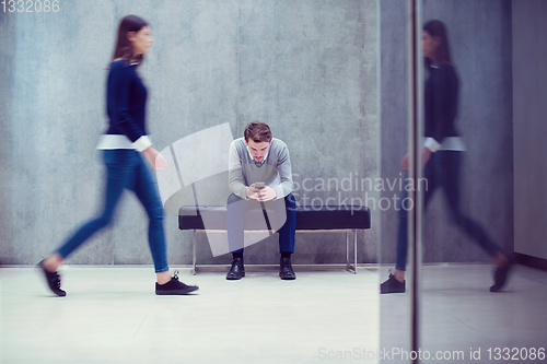 Image of businessman using mobile phone while sitting on the bench