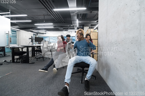 Image of multiethnics business team racing on office chairs