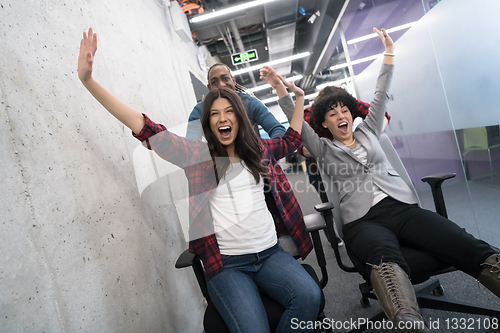 Image of multiethnics business team racing on office chairs