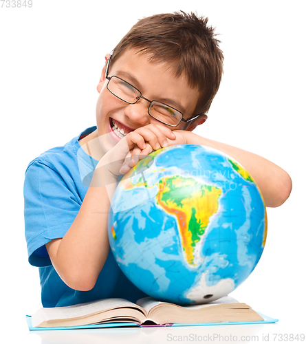 Image of Little boy is examining globe