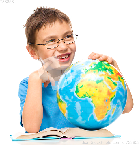 Image of Little boy is holding globe while daydreaming