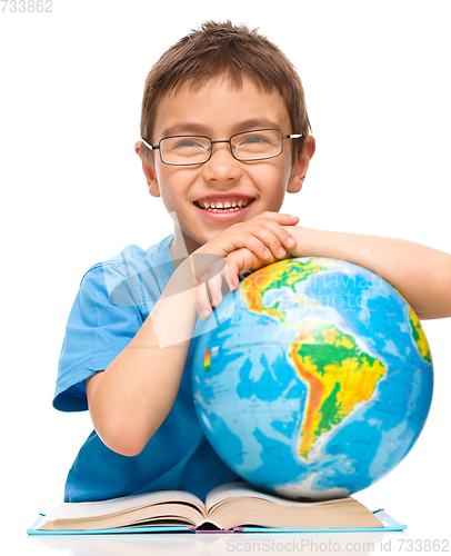 Image of Little boy is examining globe