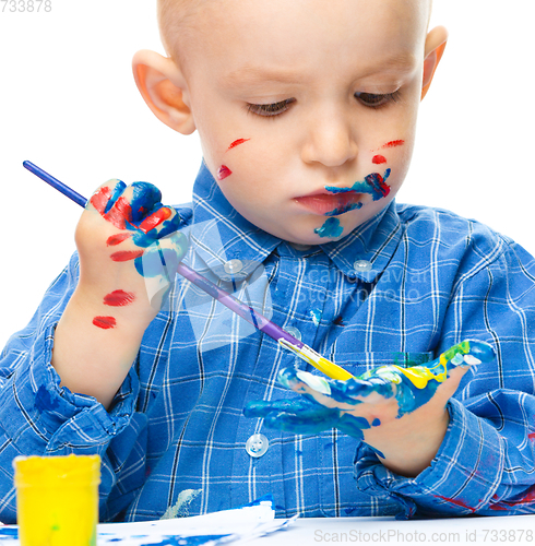 Image of Little boy is playing with paints