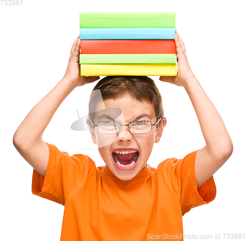 Image of Little boy is holding a pile of books