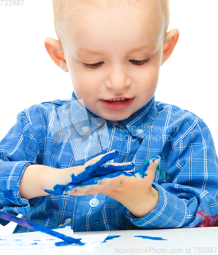Image of Little boy is playing with paints