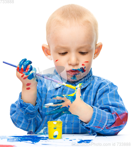 Image of Little boy is playing with paints