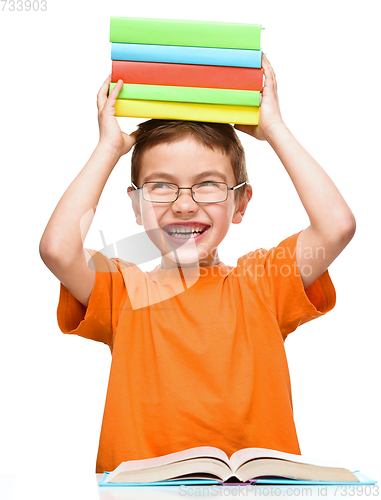 Image of Little boy is holding a pile of books