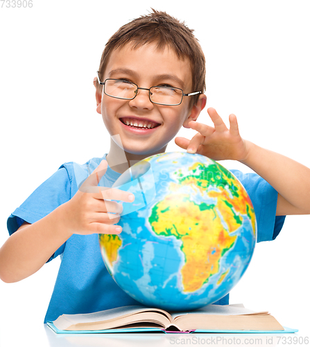 Image of Little boy is examining globe