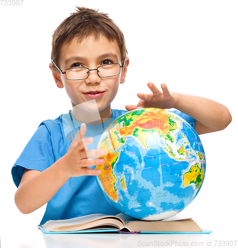 Image of Little boy is examining globe