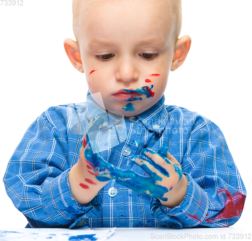 Image of Little boy is playing with paints