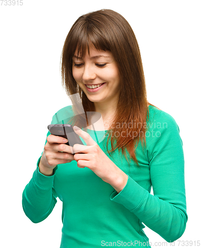Image of Young woman is typing sms message on her phone