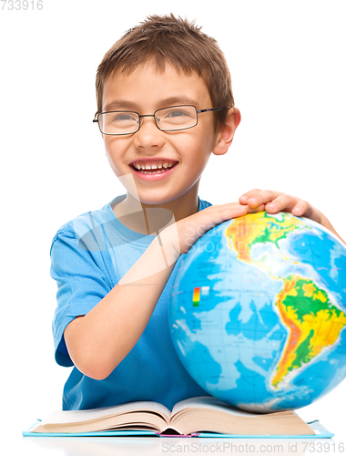 Image of Little boy is examining globe