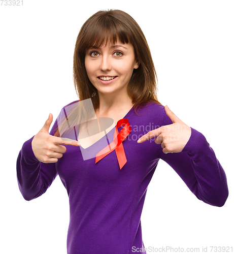 Image of Woman is pointing to the red awareness ribbon