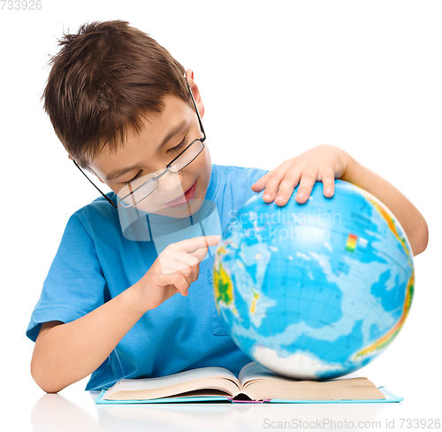 Image of Little boy is examining globe