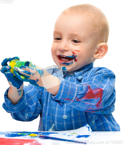 Image of Little boy is playing with paints