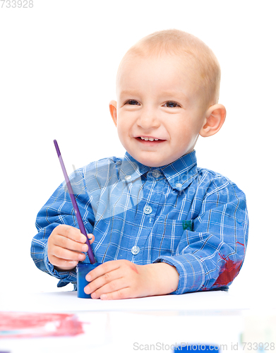 Image of Little boy is playing with paints