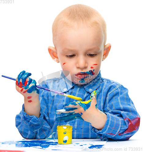 Image of Little boy is playing with paints