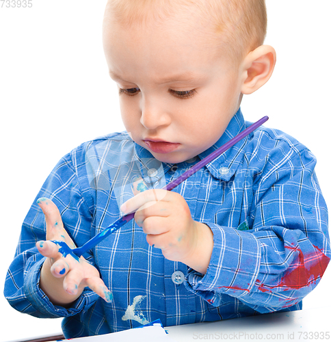 Image of Little boy is playing with paints