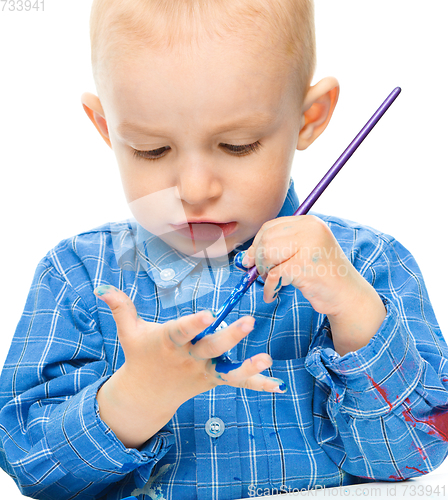 Image of Little boy is playing with paints