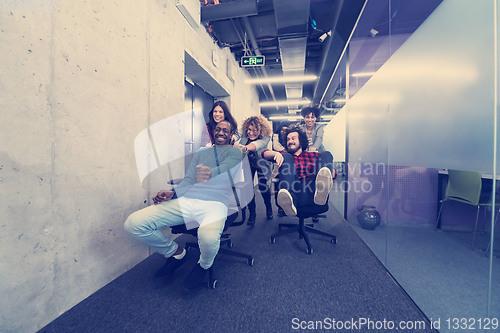 Image of multiethnics business team racing on office chairs