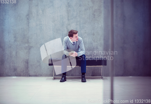 Image of businessman using smart phone while sitting on the bench