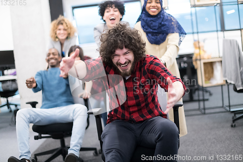 Image of multiethnics business team racing on office chairs