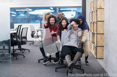 Image of multiethnics business team racing on office chairs