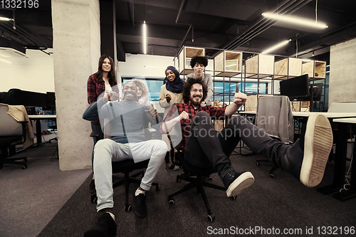 Image of multiethnics business team racing on office chairs