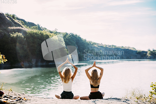 Image of Young lesbian\'s couple exercizing yoga at riverside in sunny day