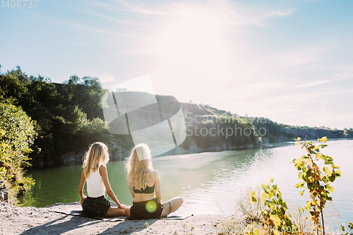 Image of Young lesbian\'s couple exercizing yoga at riverside in sunny day