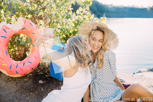 Image of Young lesbian\'s couple having fun and spending time at riverside in sunny day