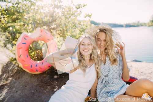 Image of Young lesbian\'s couple having fun and spending time at riverside in sunny day